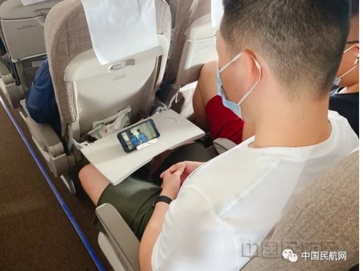 旅客用支架来手机追剧。东航客舱供图